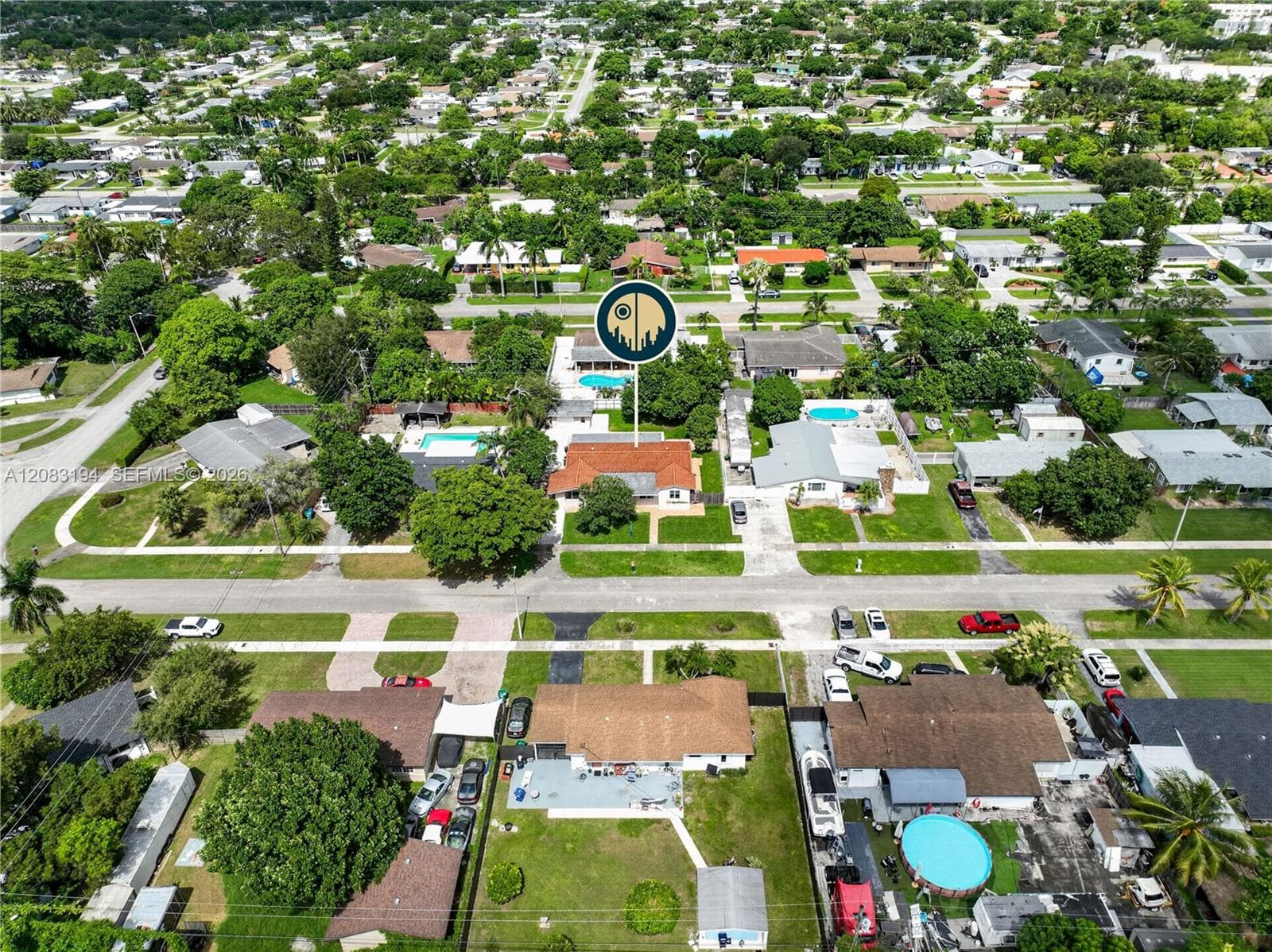 Aerial perspective featuring a single-story residence with a multi-gabled clay tile roof, paved driveway, and expansive rear lawn