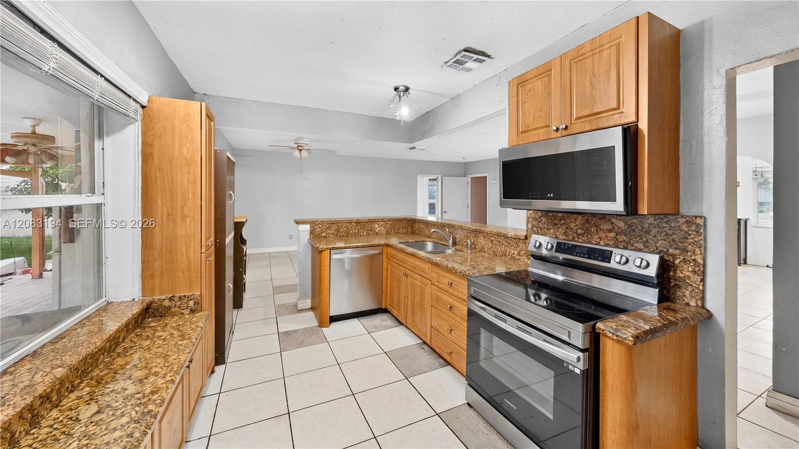 Kitchen featuring natural wood cabinetry, stone-finish countertops, tile flooring, and integrated stainless steel appliances