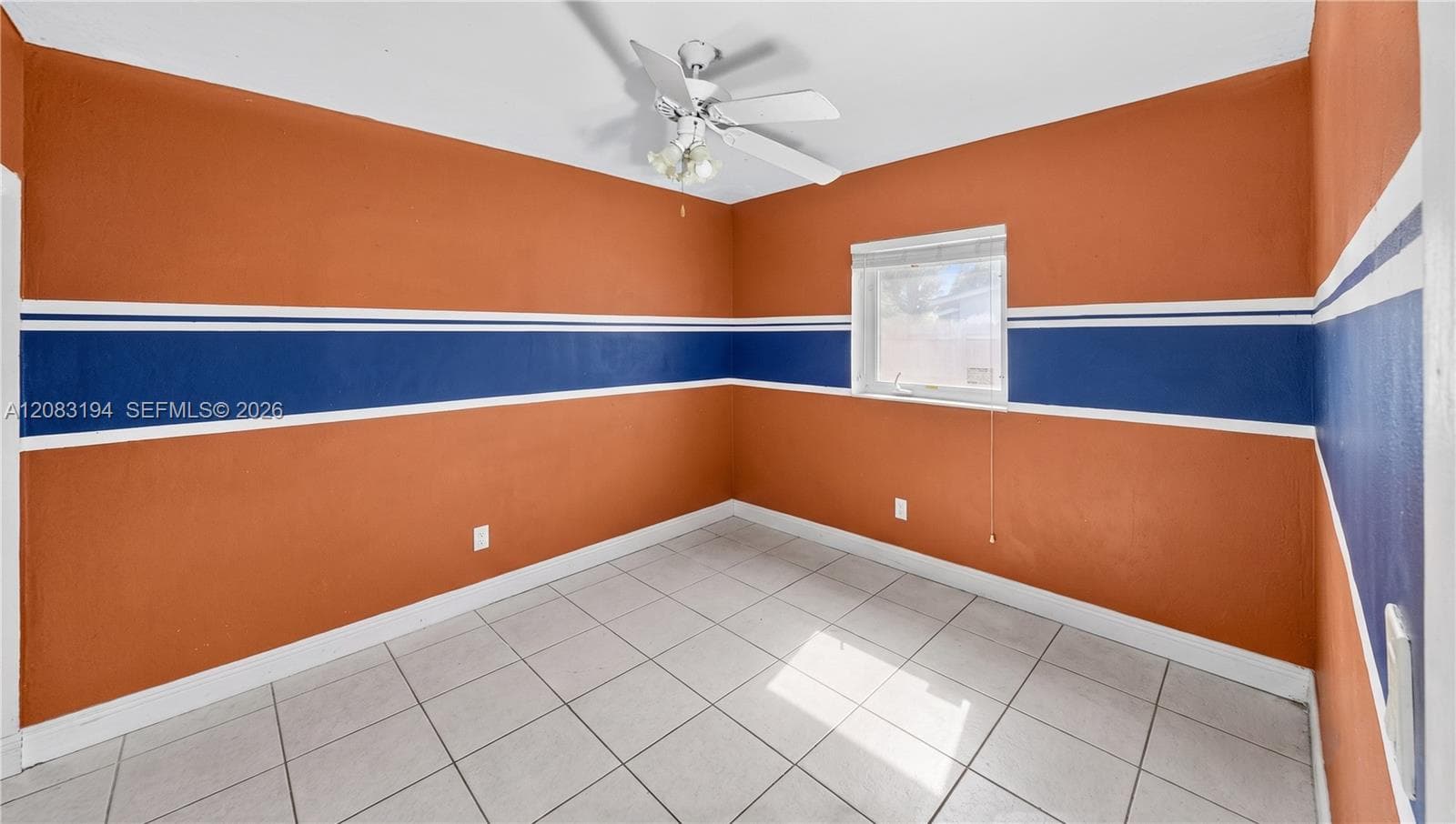 Room featuring white tile flooring, a multi-blade ceiling fan with integrated lighting, and a single-pane window
