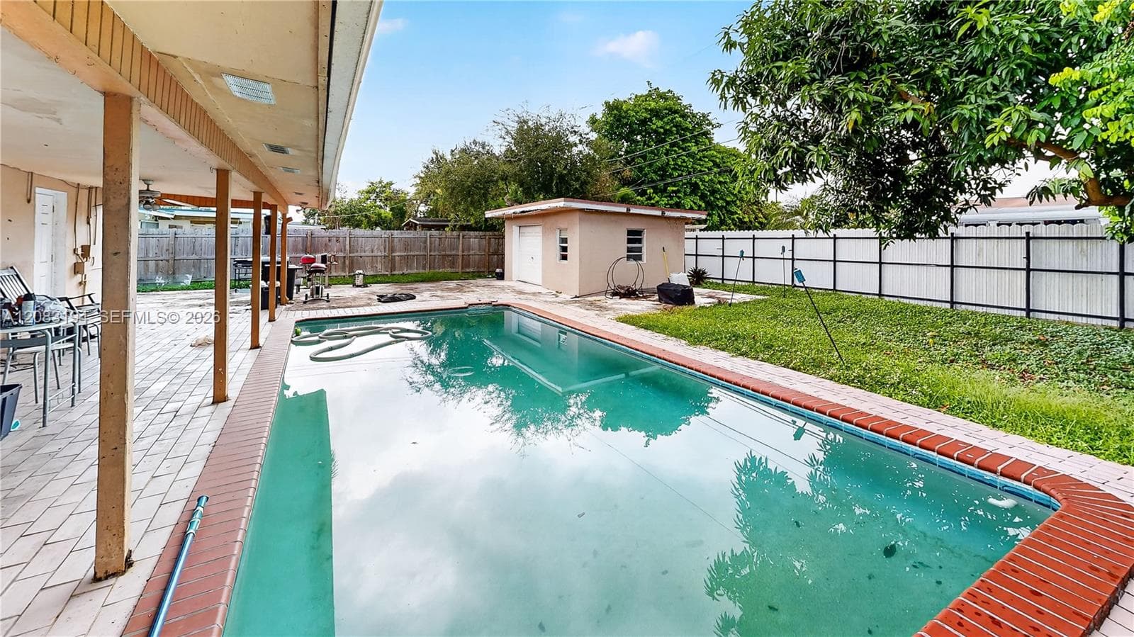 Outdoor space featuring an in-ground swimming pool, covered patio, detached structure, and perimeter fencing