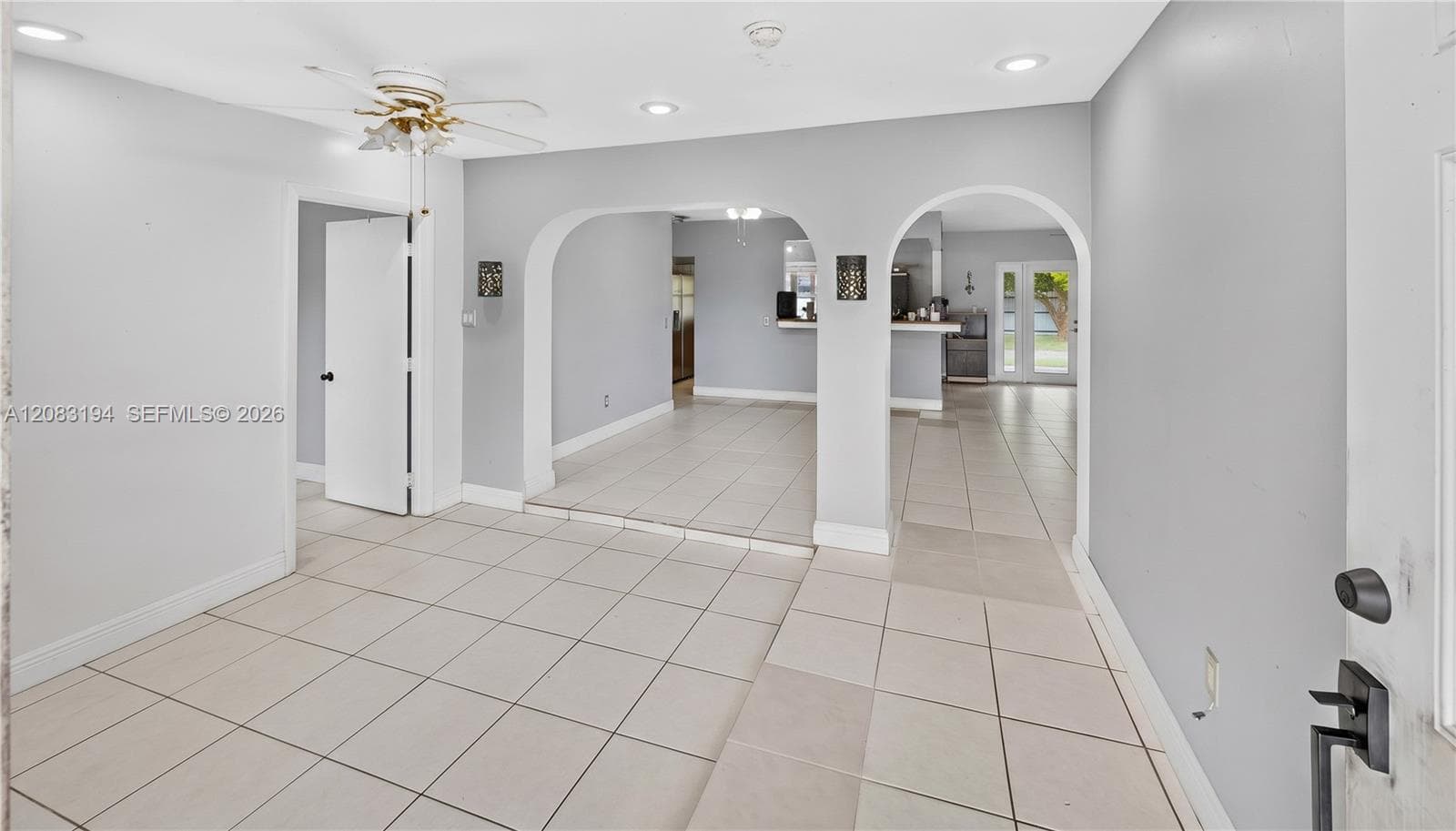 Interior space featuring large-format tile flooring, arched architectural openings, recessed lighting, and a ceiling fan