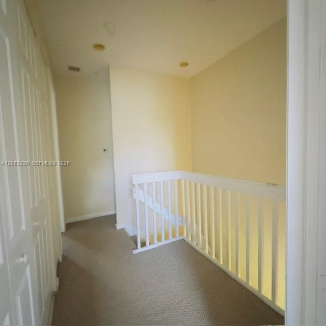 Hallway featuring neutral wall-to-wall carpeting, white paneled doors, and white wooden baluster railings
