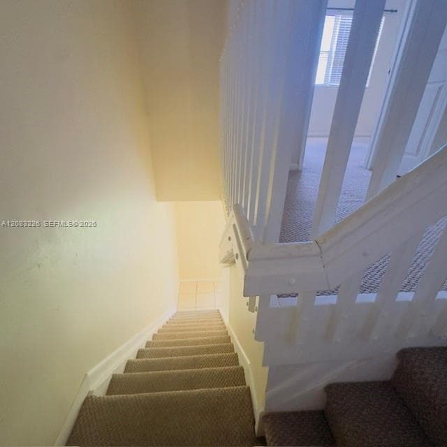 Staircase featuring wall-to-wall carpeting and a white wooden balustrade with a matching handrail