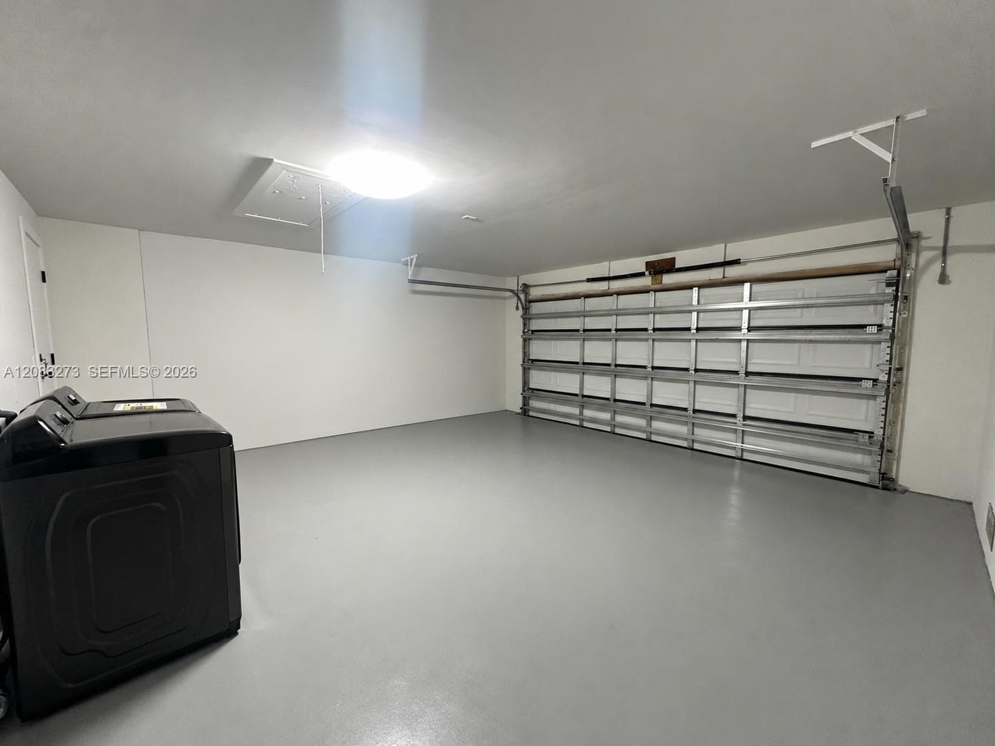 Attached garage featuring a seamless epoxy-coated floor, white paneled garage door, and recessed ceiling lighting