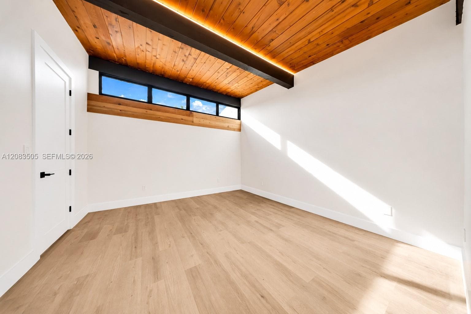 Vaulted wood-plank ceiling featuring exposed structural beams, clerestory windows, integrated cove lighting, and wood-finish flooring