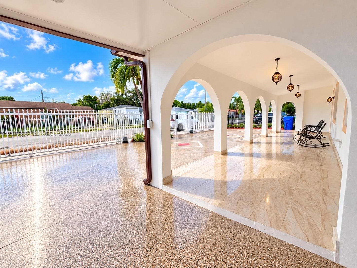 Elegant covered loggia with soaring barrel-vaulted ceilings and a series of arched openings, polished concrete flooring throughout, and decorative pendant lighting