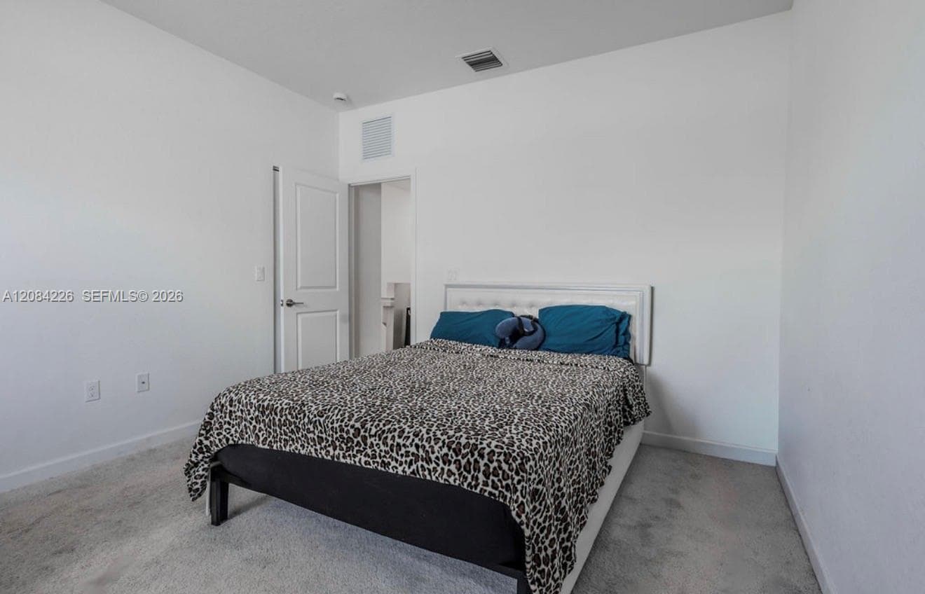 Neutral interior room featuring neutral carpeting, a white paneled door, and smooth walls