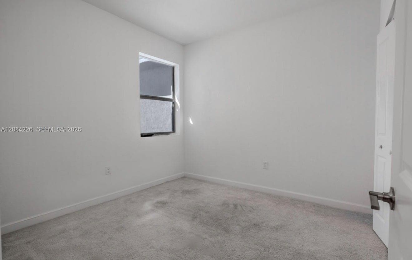 Neutral-toned carpet flooring, single-pane window, and a built-in closet with a panel door