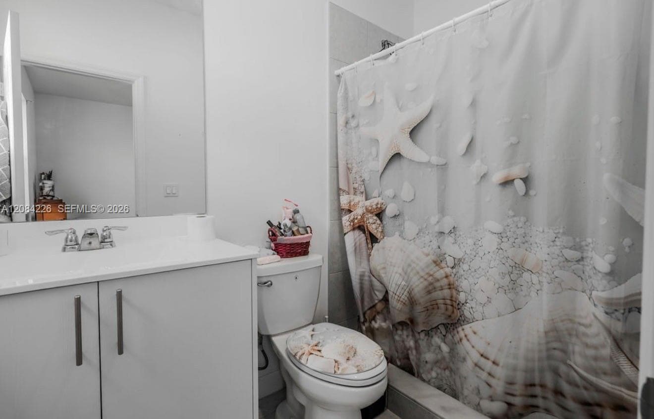 Bathroom featuring a white vanity cabinet, solid-surface countertop with an integrated basin, dual-handle chrome faucet, and a tiled shower surround