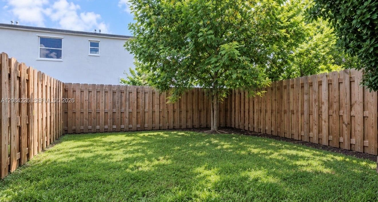 Private backyard featuring a tall wood privacy fence and a mature shade tree