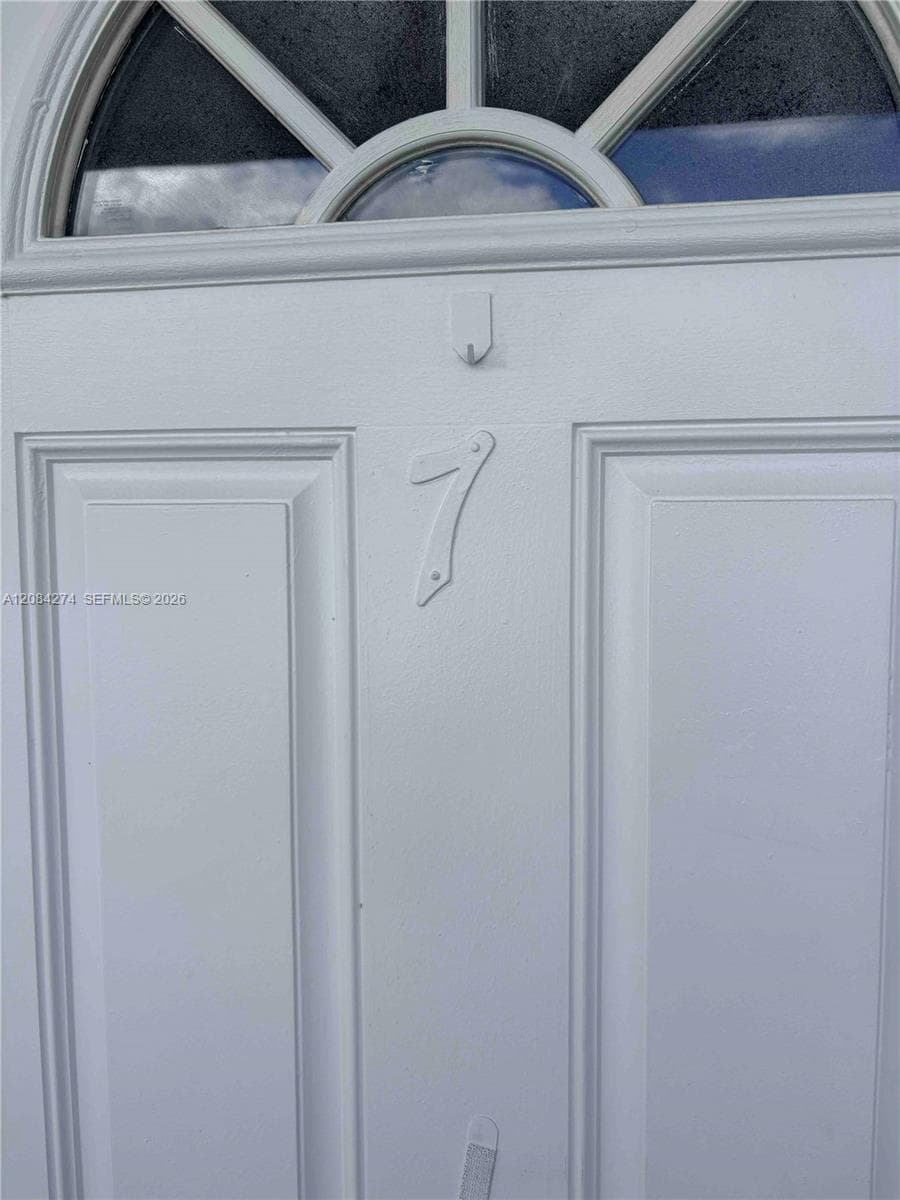 White paneled door with an arched transom window featuring decorative muntins