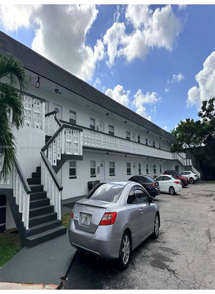 Multi-story building featuring white exterior, dark pitched roof, and white balcony railings