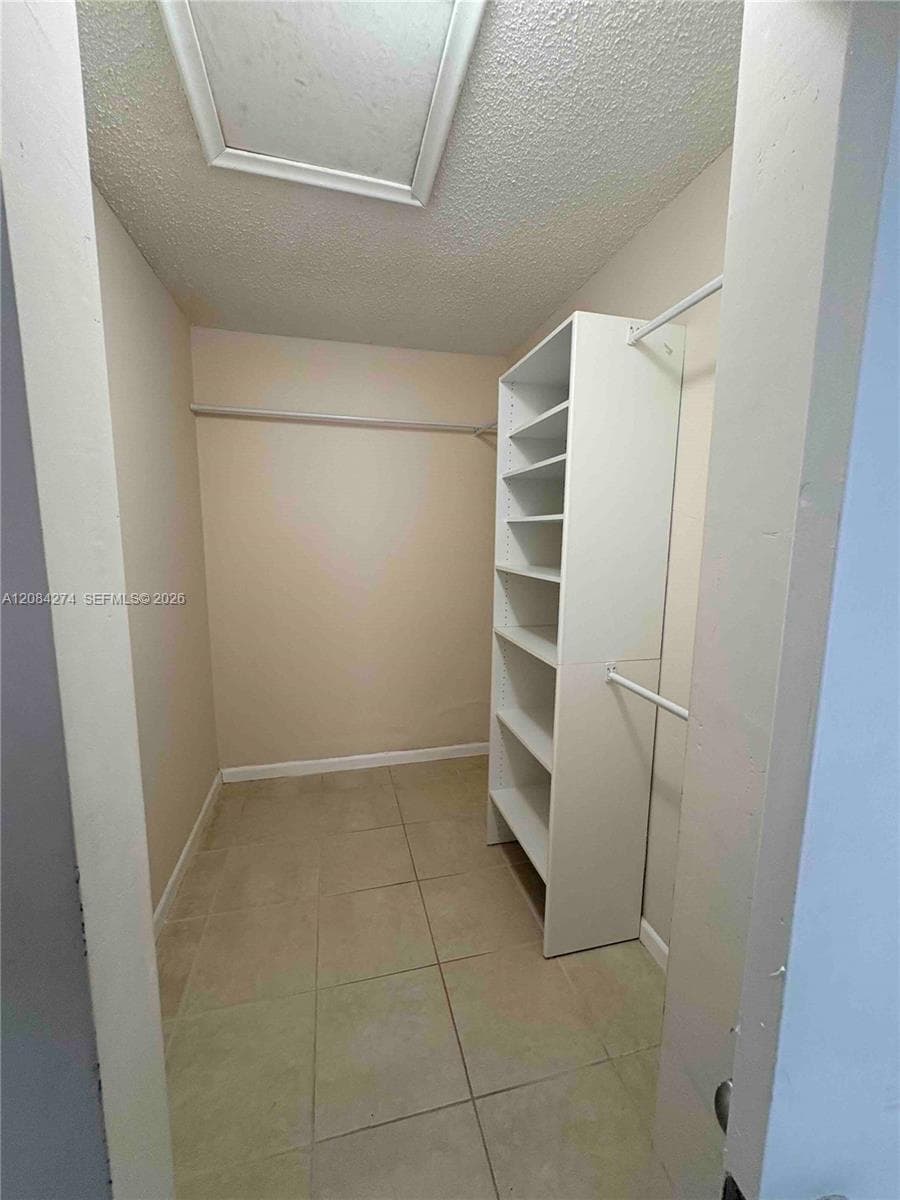 Walk-in closet with built-in shelving, hanging rods, and tile flooring