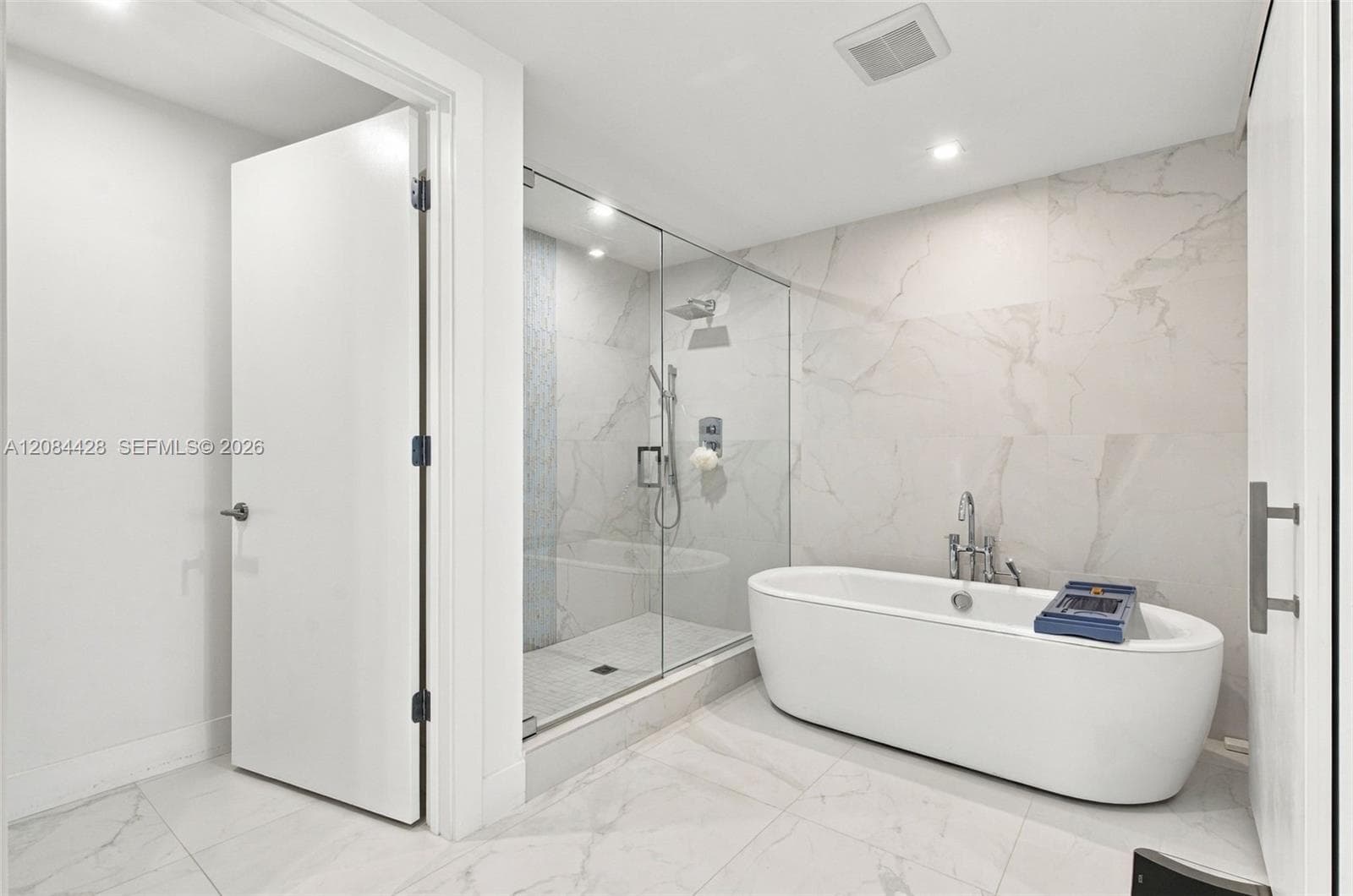 Spa-like primary bathroom with a freestanding soaking tub and glass-enclosed shower.