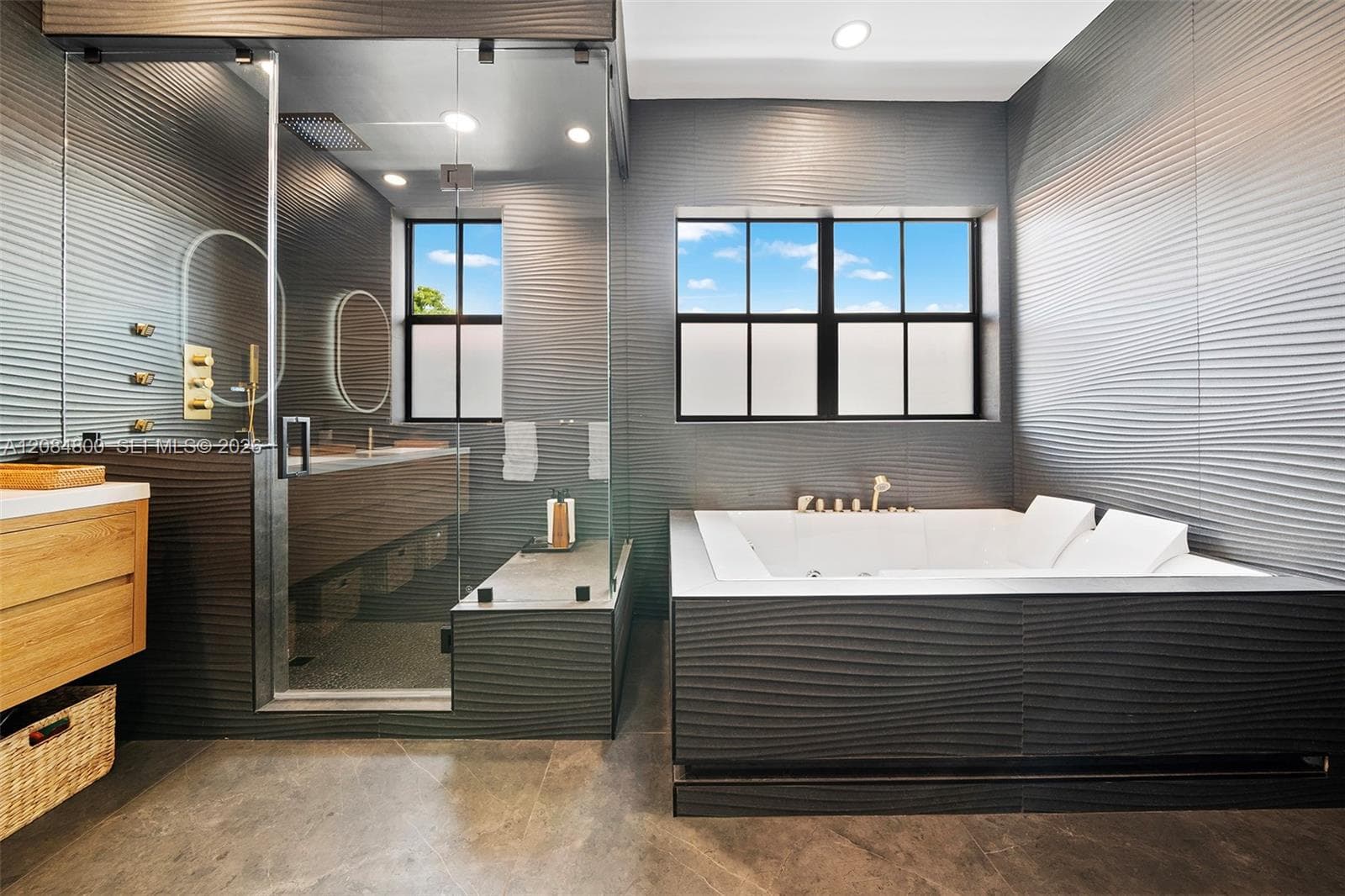 Spa-inspired primary bath with glass rain shower and deep soaking tub — part of the full renovation of this one-story residence