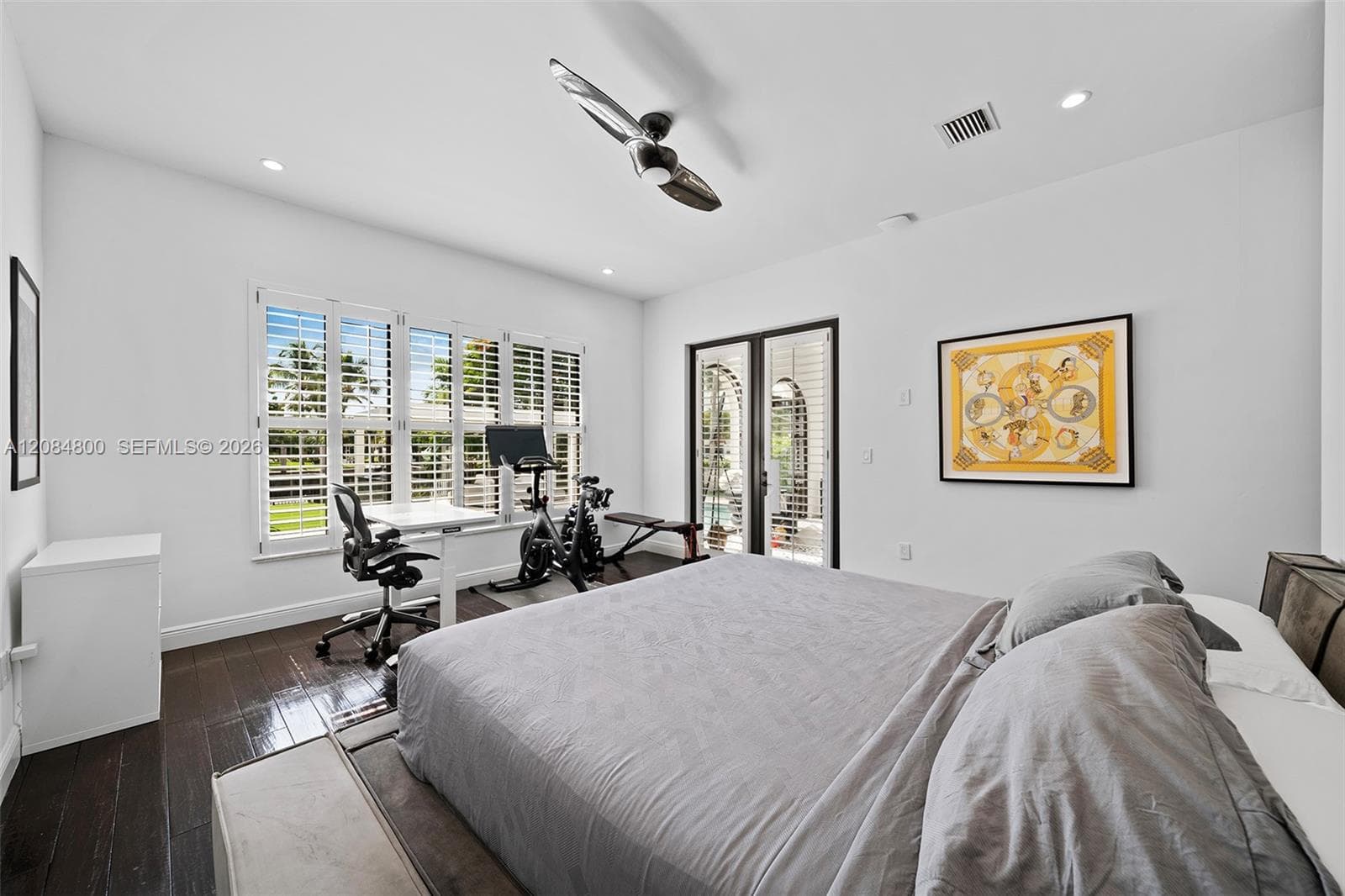Primary bedroom with plantation shutters, garden views and glass doors to the outdoors