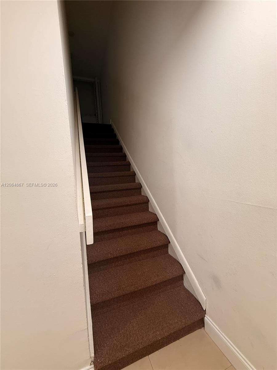 Staircase featuring wall-to-wall carpeting and a white painted handrail