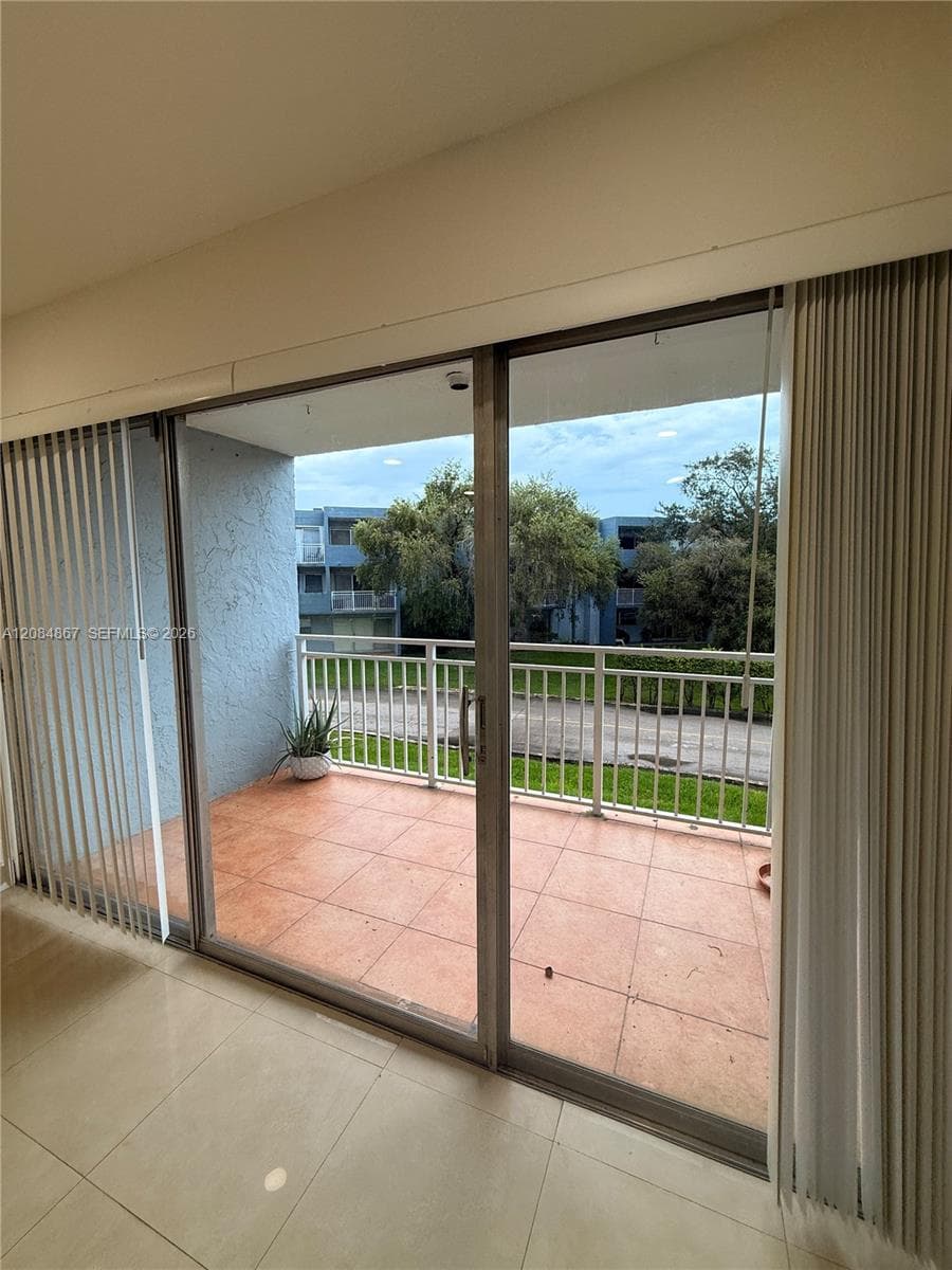 Sliding glass door access to a balcony with terracotta-style tile flooring and metal railings