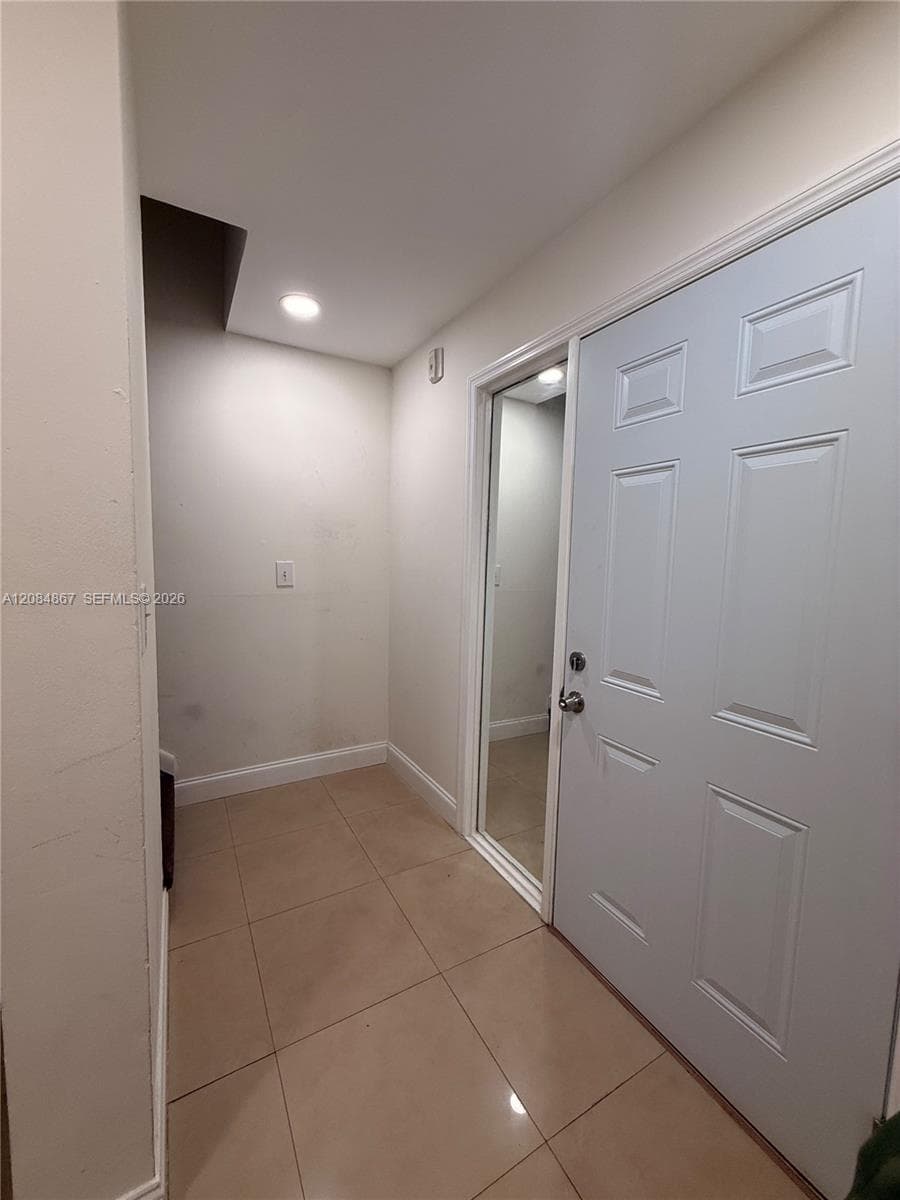 Entryway featuring large-format tile flooring, recessed ceiling lighting, a six-panel door, and a full-length mirrored closet door