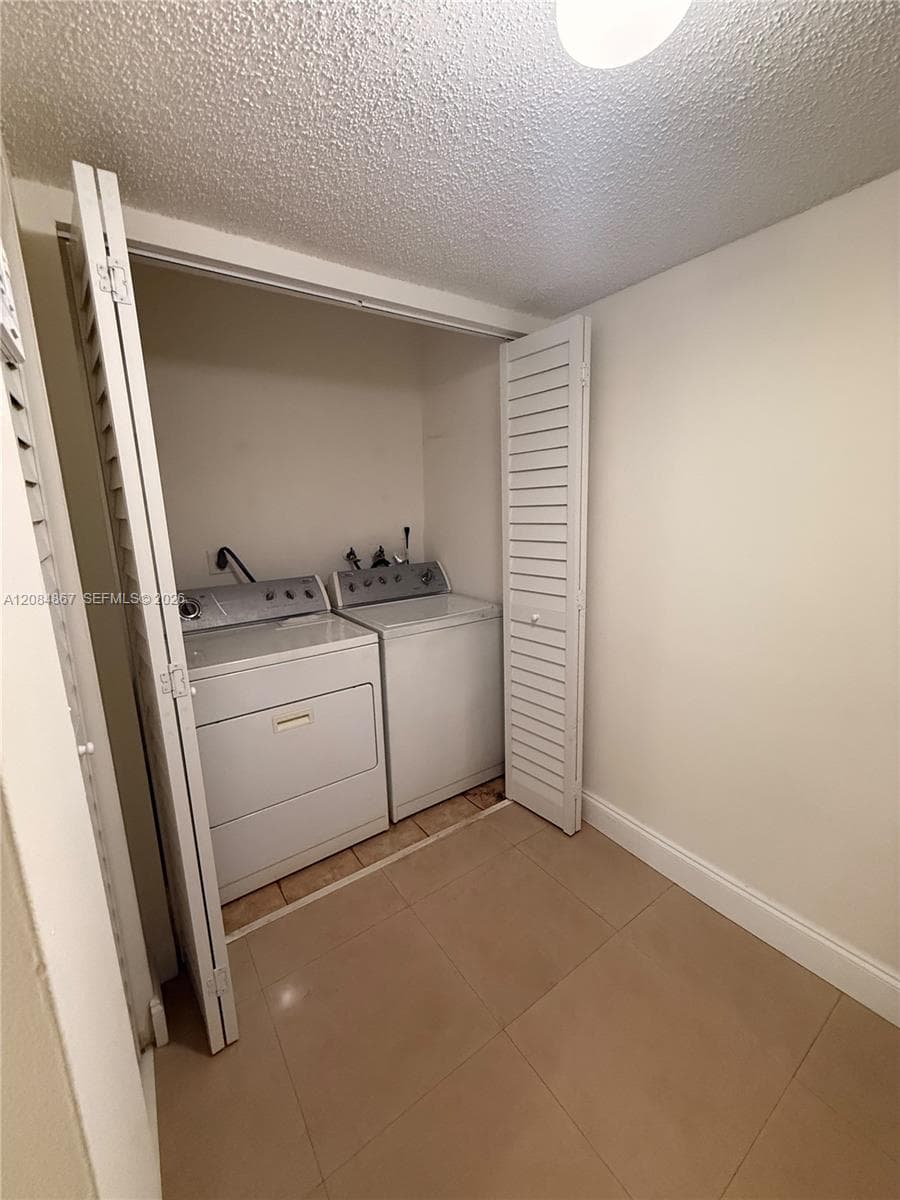 Laundry closet featuring louvered bi-fold doors, large-format tile flooring, and integrated laundry hookups