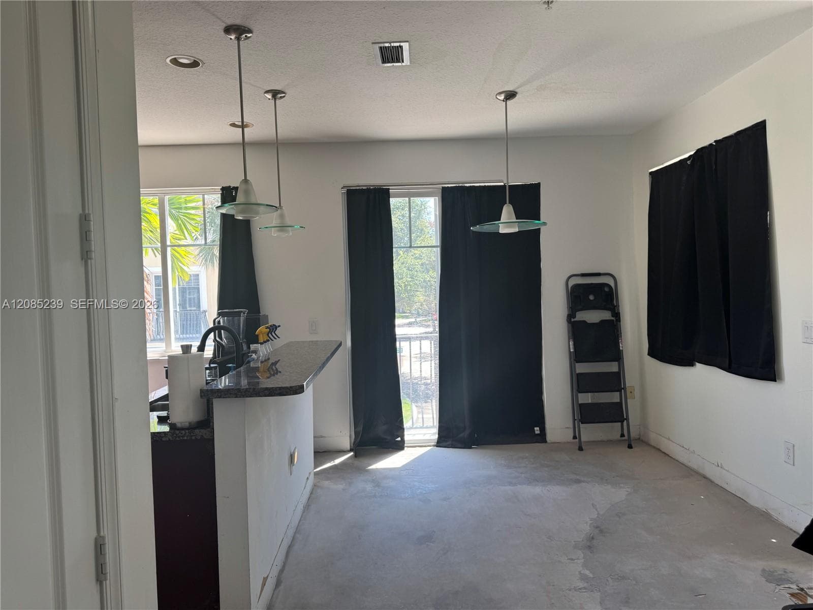 Kitchen featuring a stone-surface breakfast bar, recessed lighting, and three glass pendant light fixtures, complemented by sliding glass doors providing outdoor access