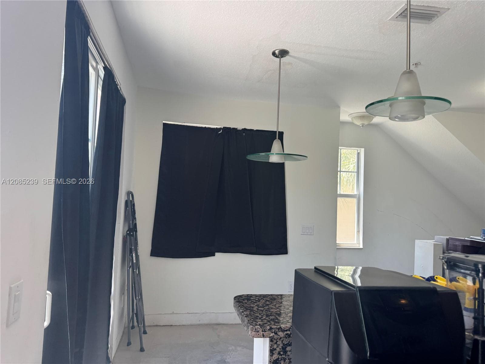 Interior space featuring a stone-finish countertop, dual glass-pendant lighting fixtures, and multiple windows