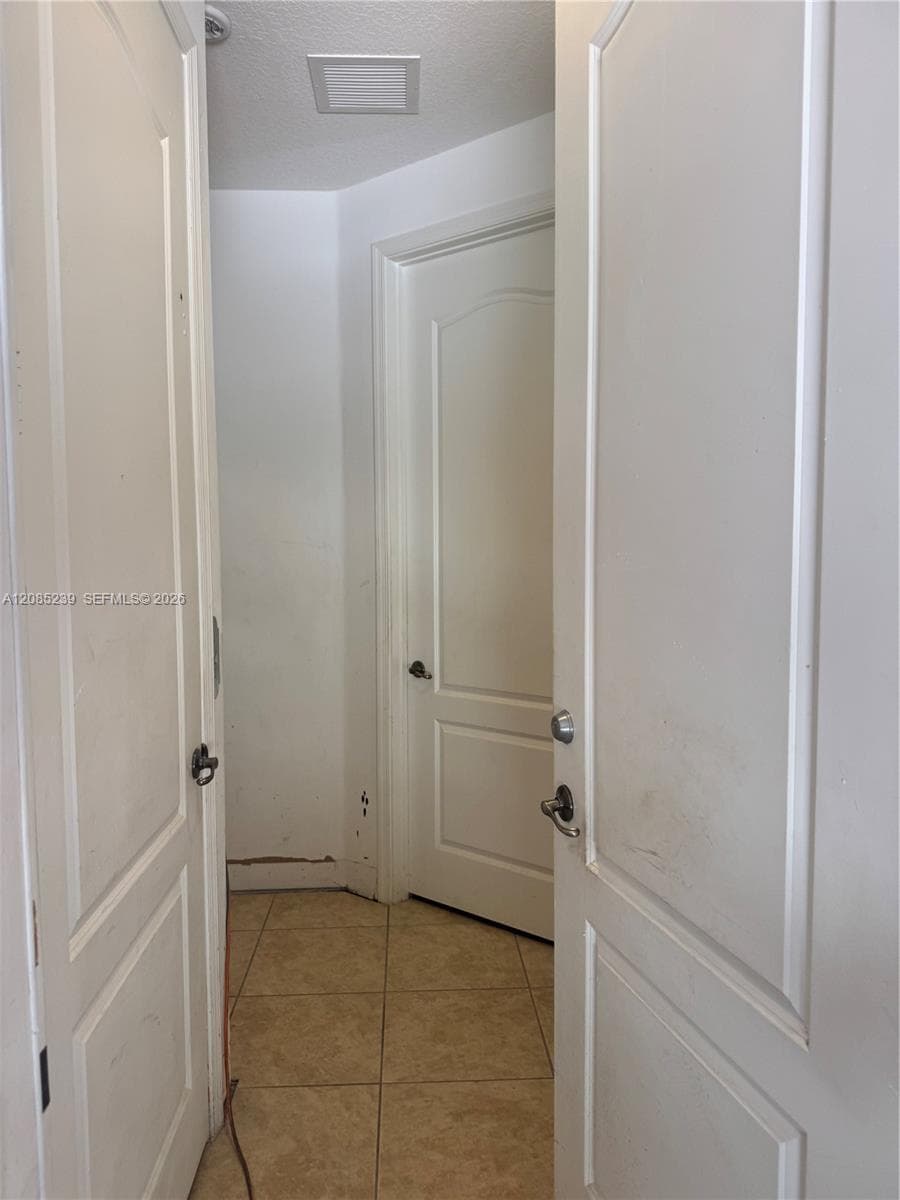 Interior hallway featuring three-panel arched doors with metal hardware and neutral-toned floor tile