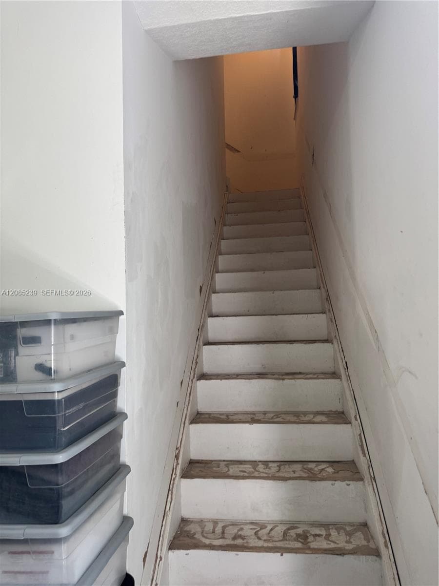 Straight wooden staircase with white painted treads and vertical wall enclosures