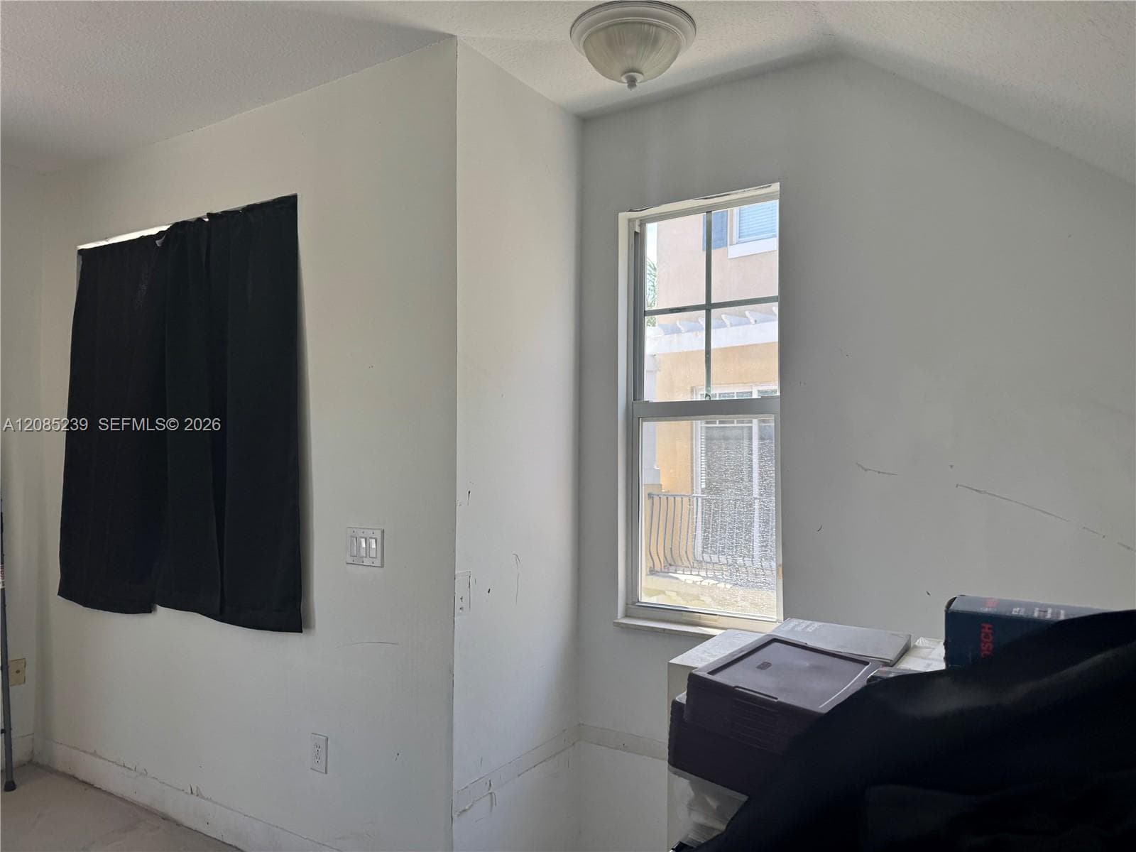 Room featuring angled ceiling, single-pane window with muntins, and flush-mount lighting