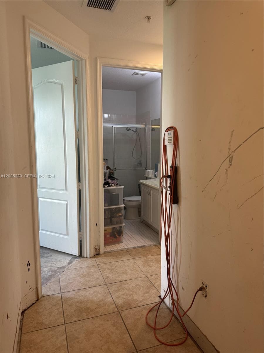 Neutral-tone tile flooring, solid-core interior doors, and built-in bathroom vanity with an integrated sink
