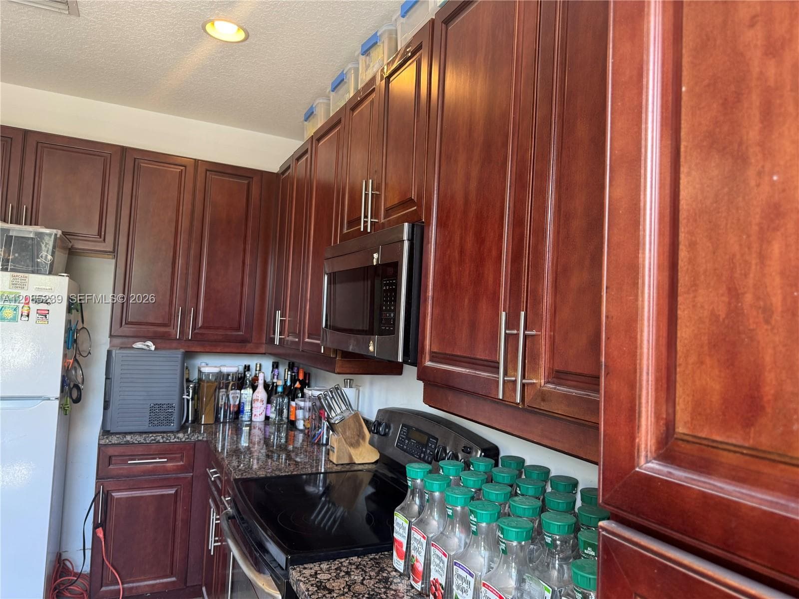 Kitchen featuring dark-toned cabinetry, stone-finish countertops, stainless steel appliances, and recessed ceiling lighting