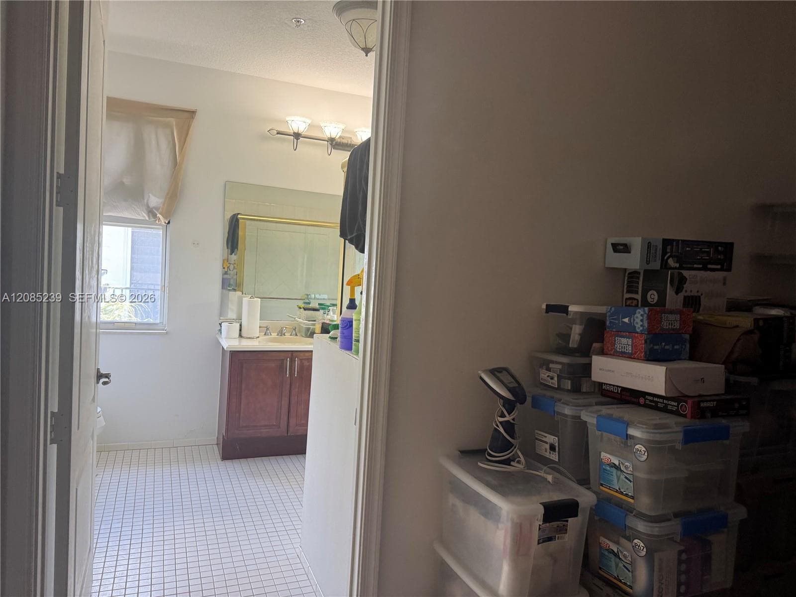 Bathroom featuring a vanity with wood-finish cabinetry, a white countertop with an integrated sink, a rectangular wall mirror, and tile flooring