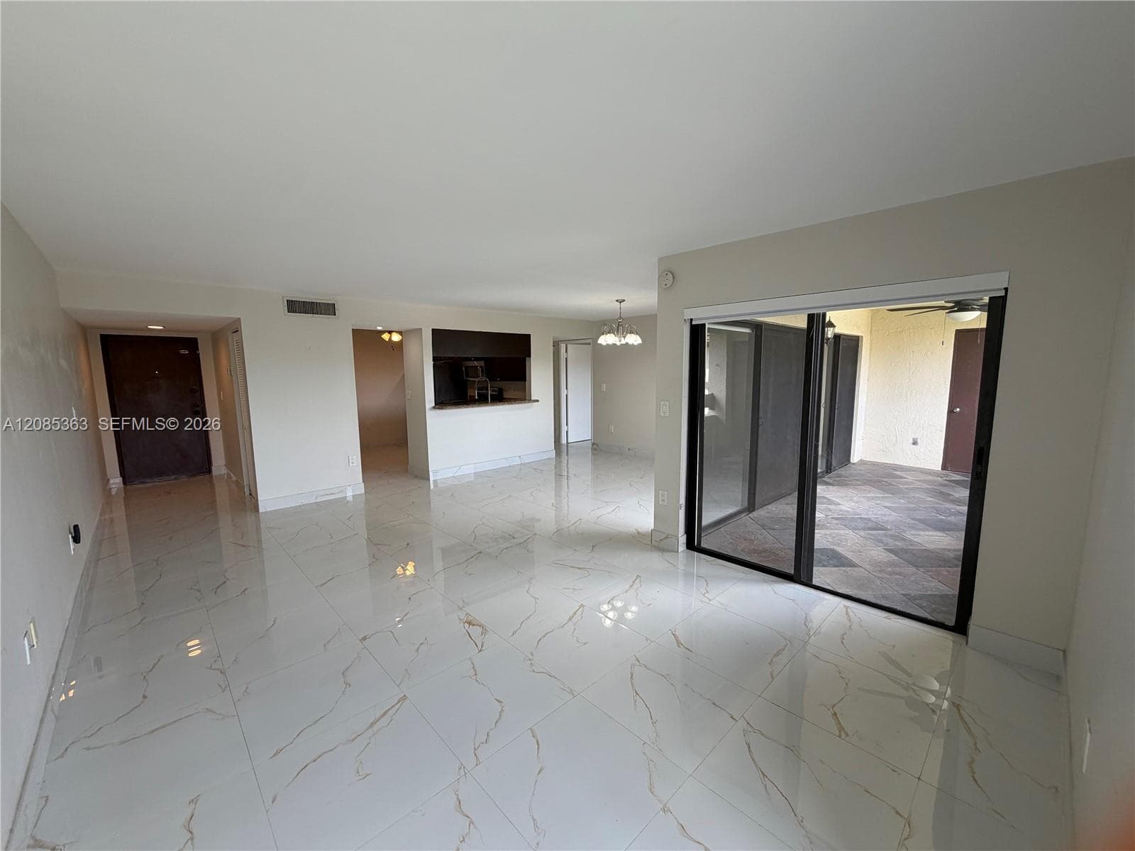 Large-format porcelain tile flooring with veining, sliding glass door, and interior pass-through window to kitchen