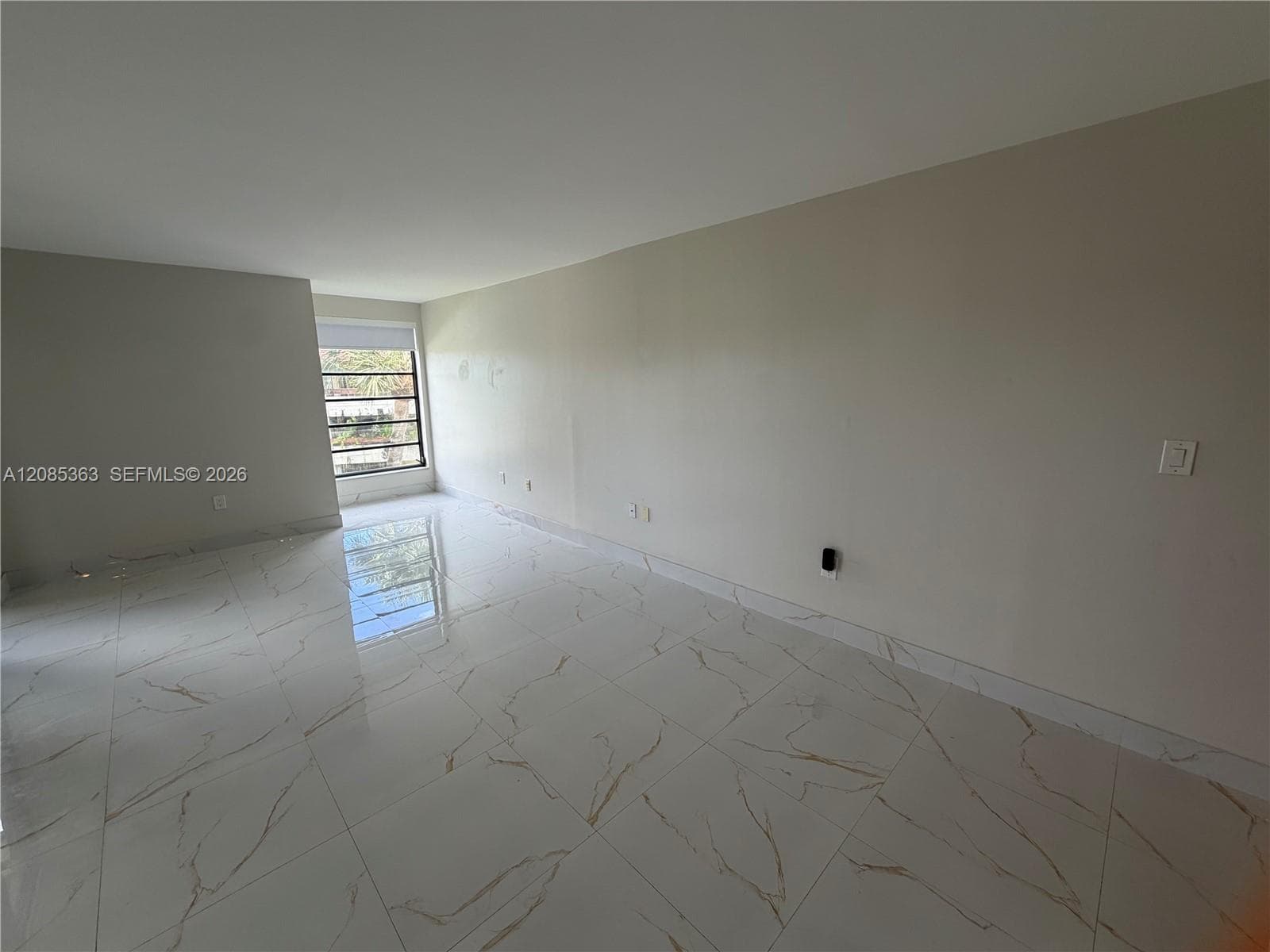 Large format, polished porcelain tile flooring with marble-style veining and a single, multi-pane window
