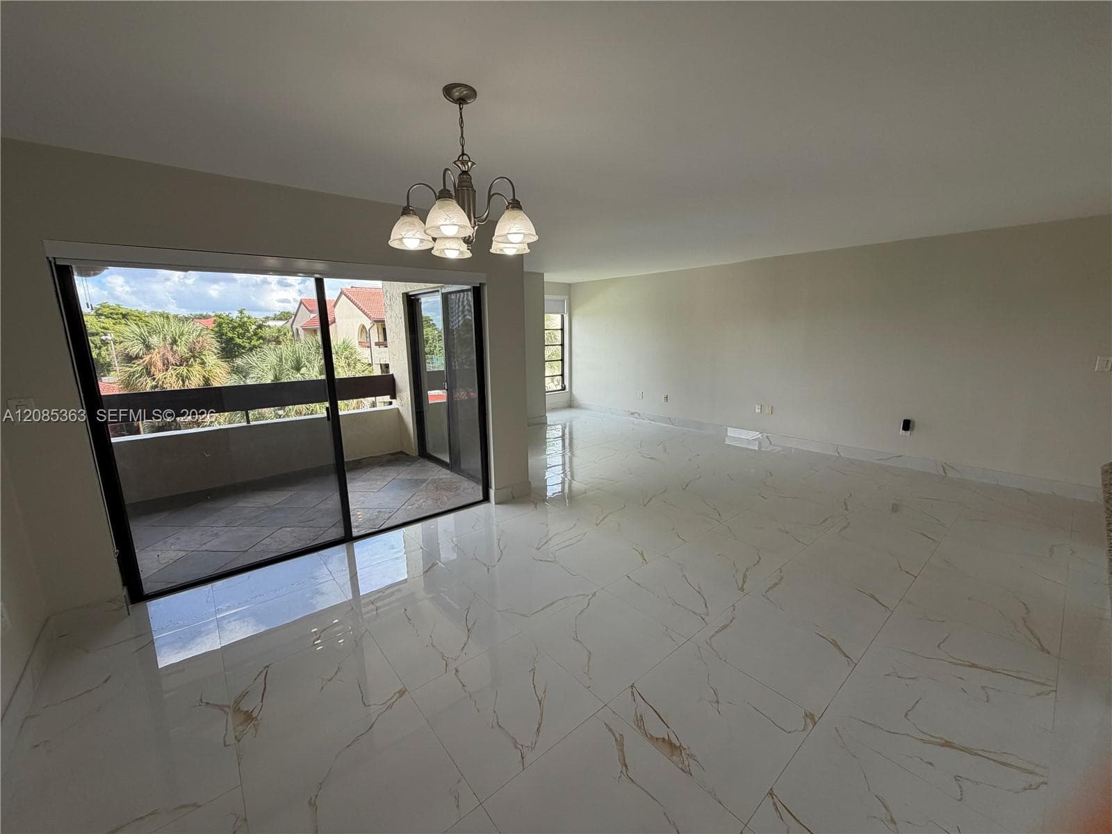 Polished porcelain tile flooring with veining, multi-arm chandelier, sliding glass door, and exterior balcony