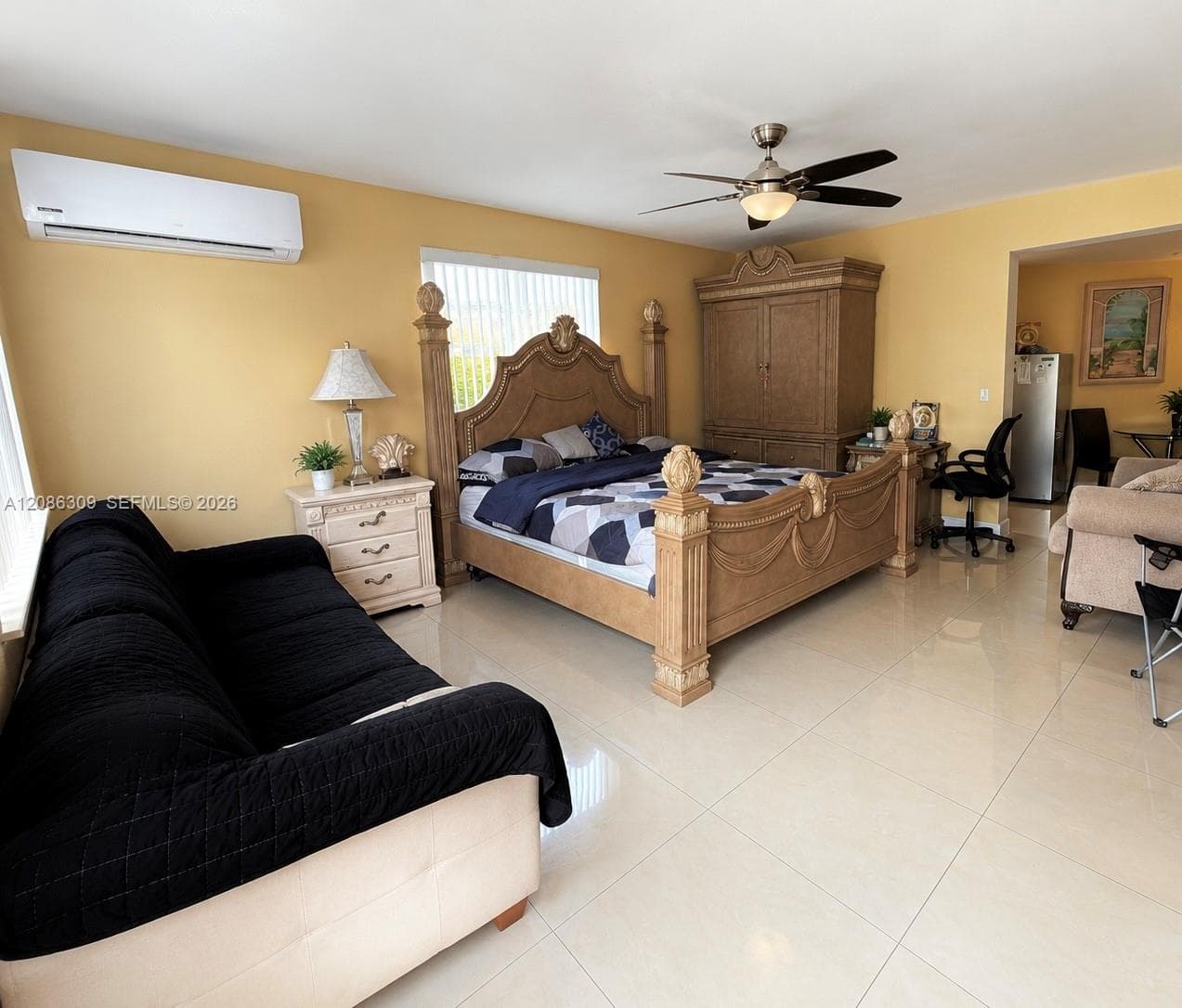 Spacious room featuring light-toned tile flooring, wall-mounted ductless air conditioning unit, and a ceiling fan with integrated lighting