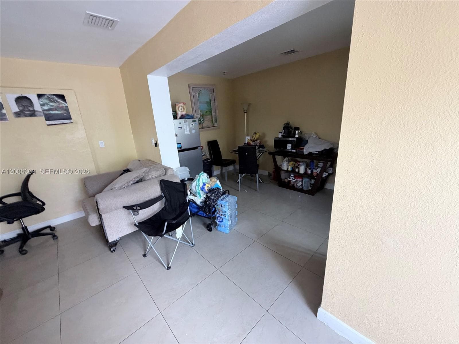 Large-format ceramic tile flooring throughout, finished with neutral wall paint and a structural cased opening