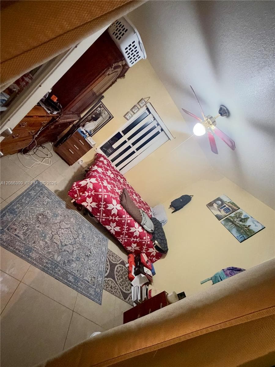 Ceramic tile flooring, white horizontal window blinds, and a multi-blade ceiling fan with integrated lighting