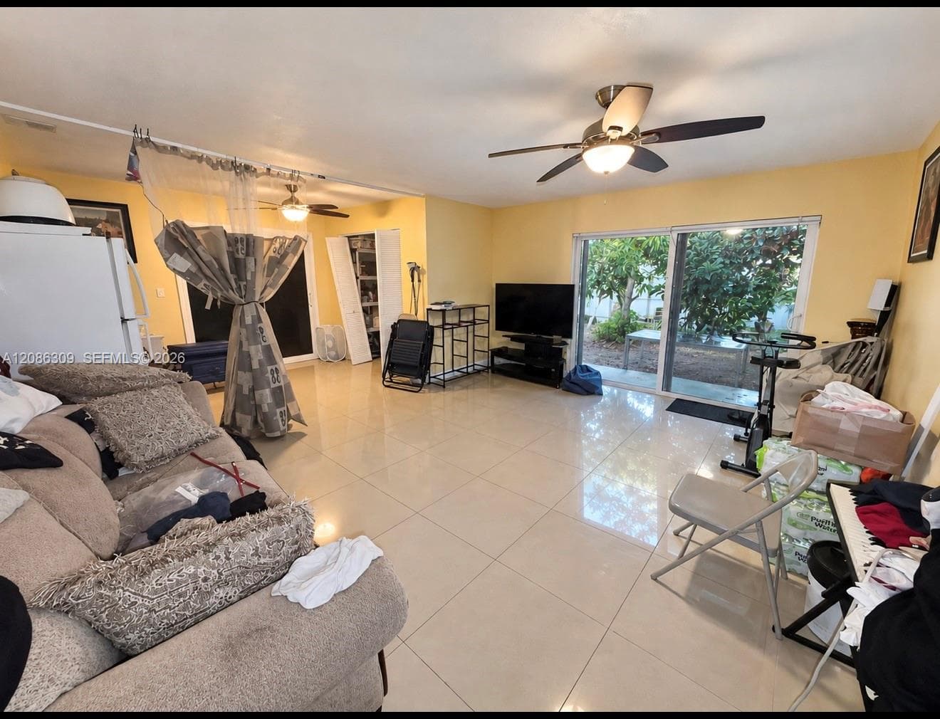 Large format tile flooring, dual ceiling fans with integrated lighting, and expansive sliding glass doors leading to the exterior