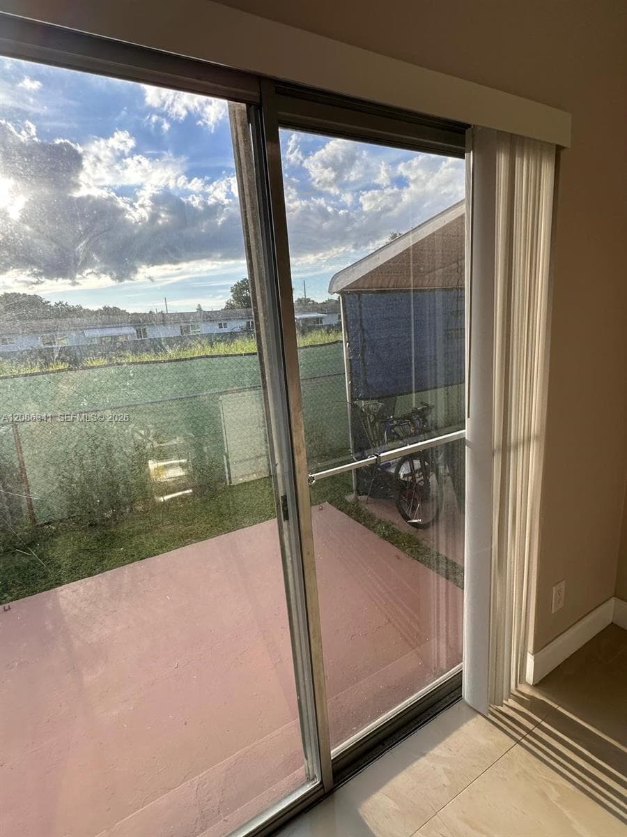 Sliding glass door with a metal frame, exterior concrete patio, and fenced outdoor area