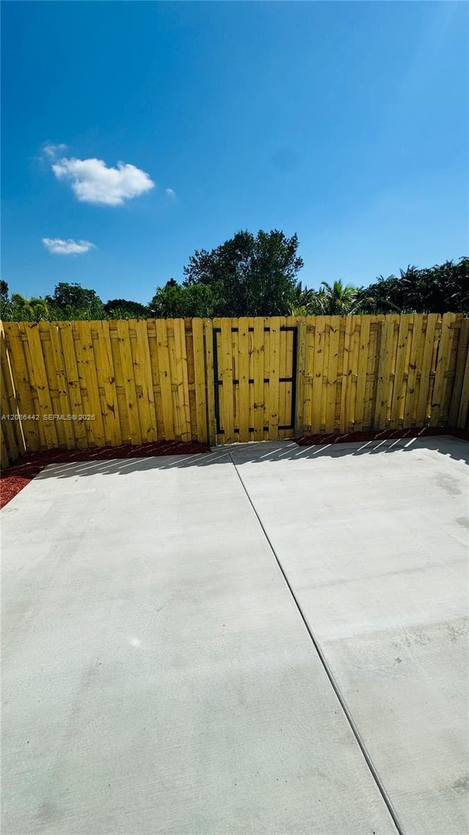 Concrete patio featuring a wood-panel fence with an integrated gate