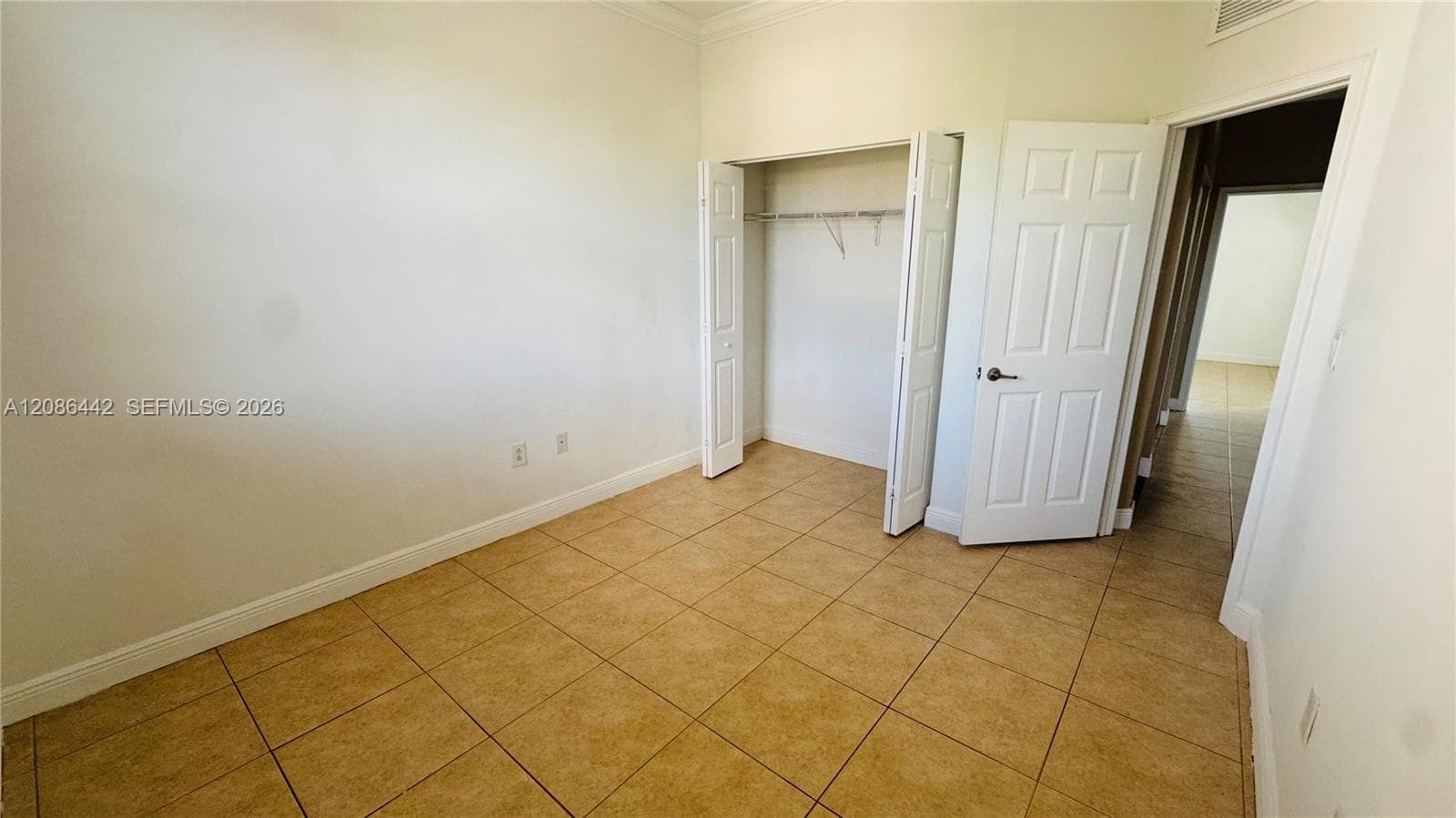 Room interior featuring neutral walls, large-format tile flooring, a bi-fold closet door, and a six-panel interior door