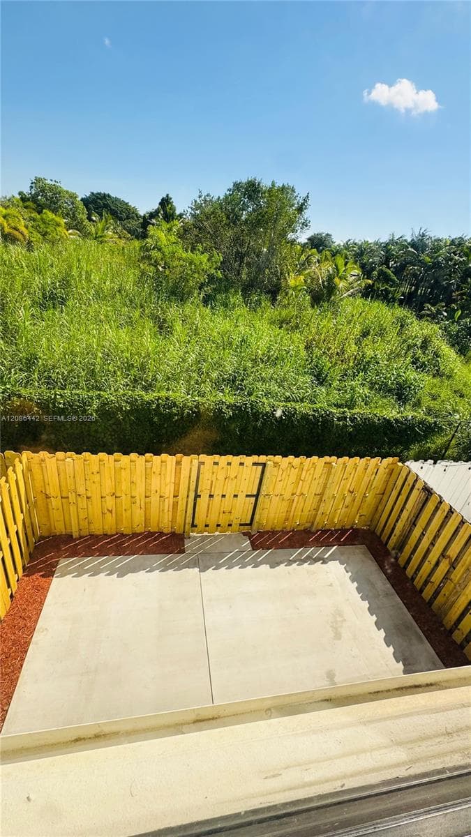 Concrete patio enclosed by a wood privacy fence featuring a gate