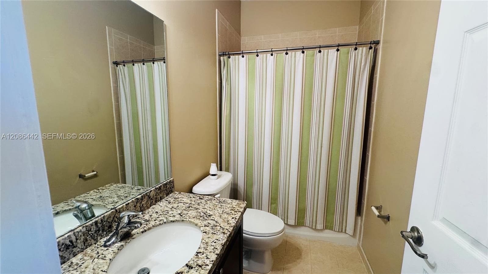 Bathroom featuring a vanity with a stone-finish countertop, under-mount sink, large wall-mounted mirror, and a tile-surround shower