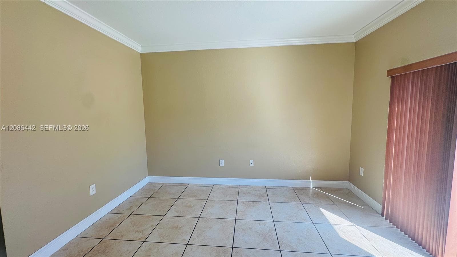 Room featuring large-format neutral tile flooring, crown molding, and vertical blinds