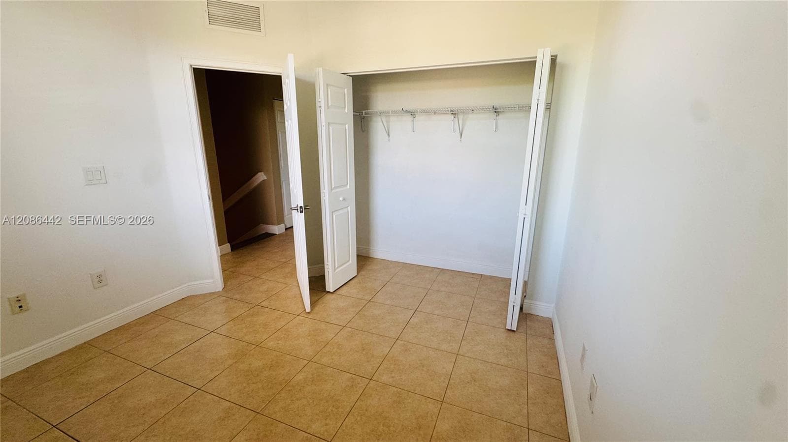 Room featuring neutral tile flooring, bi-fold closet doors, and integrated wire shelving