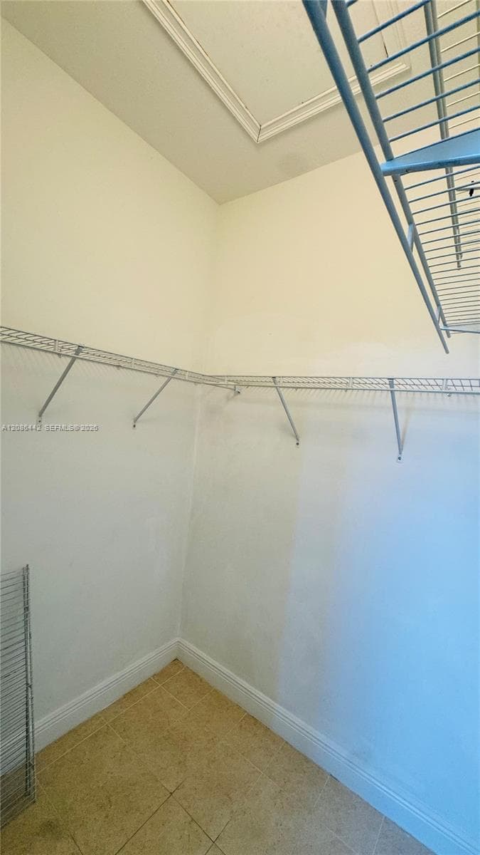 Storage space featuring wall-mounted wire shelving and tile flooring