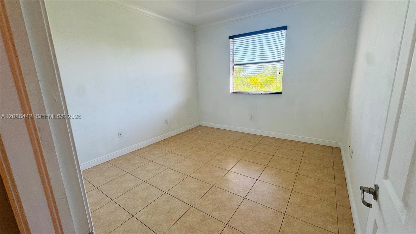 Neutral-toned tile flooring, tray ceiling, and a single-hung window with integrated blinds