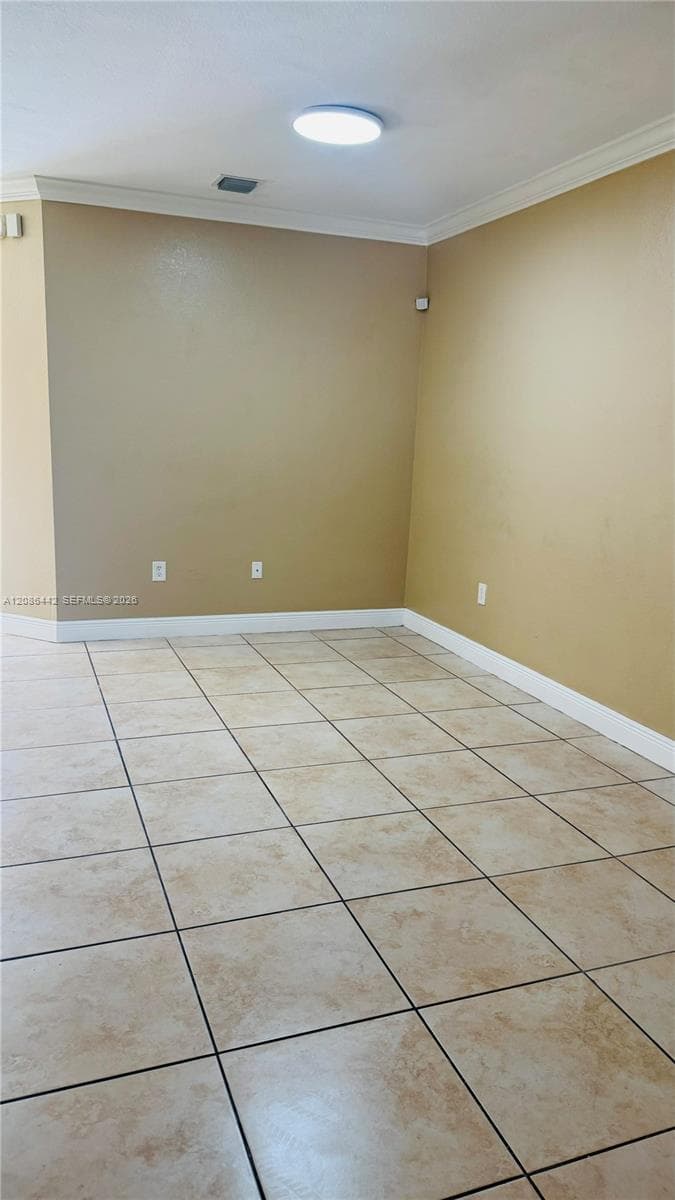 Neutral interior space featuring ceramic tile flooring, crown molding, and a flush-mount ceiling light fixture
