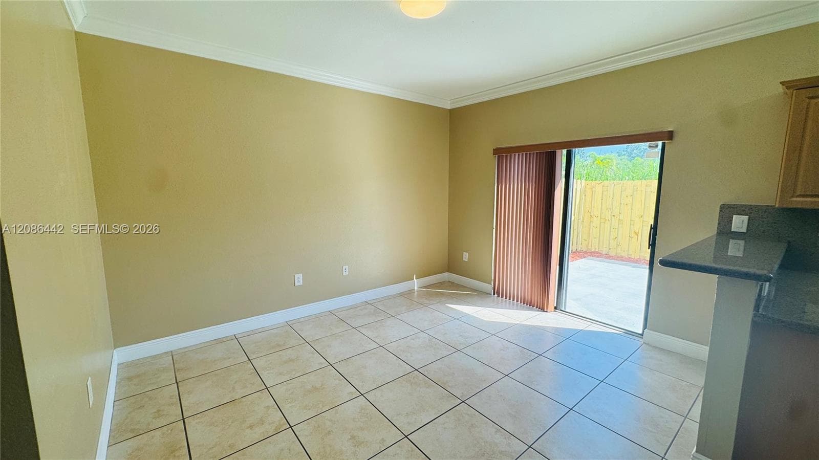 Neutral-tone room featuring ceramic tile flooring, crown molding, and sliding glass doors with vertical blinds